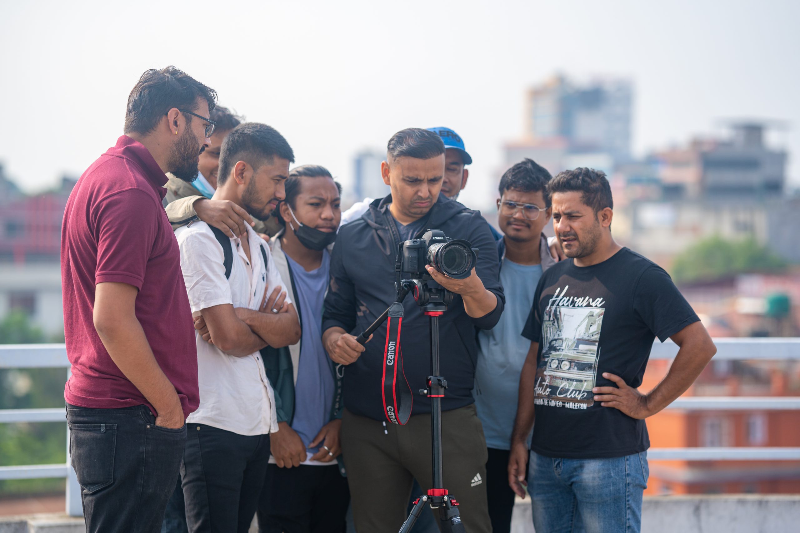 a group of men standing around a camera